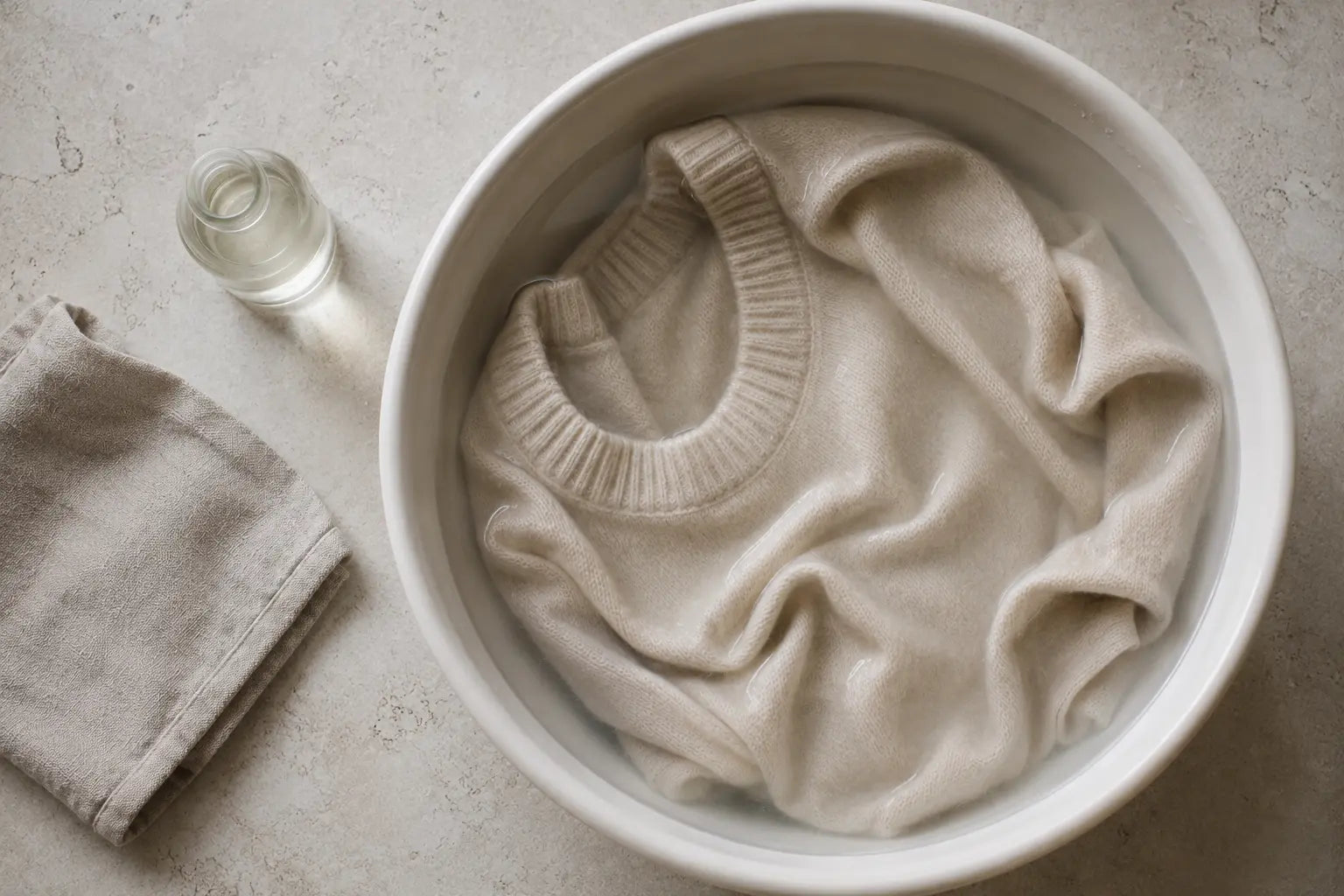 A cream cashmere sweater soaking in a basin of cool water