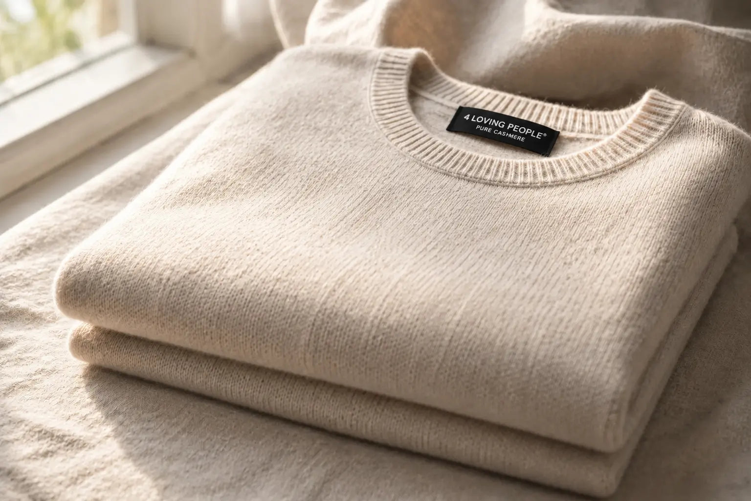 Soft oatmeal cashmere sweater folded in morning light, showing a smooth, non-itchy knit texture