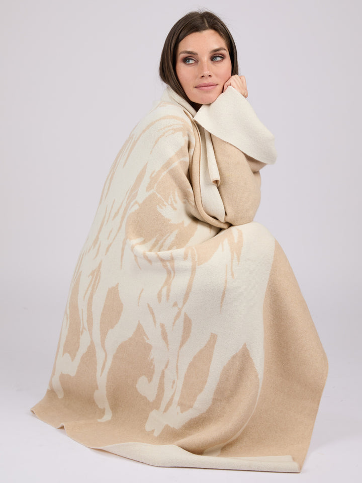 A rectangular cashmere blanket featuring a stylized silhouette of a herd of horses in motion, rendered in a muted oat on a warm pearl background #PEARL/OAT