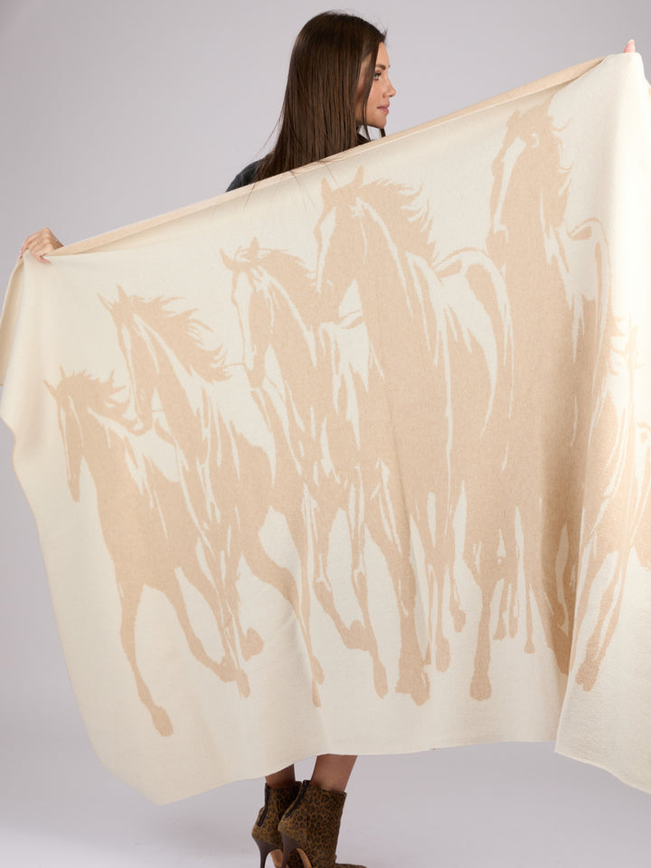 A rectangular cashmere blanket featuring a stylized silhouette of a herd of horses in motion, rendered in a muted oat on a warm pearl background #PEARL/OAT